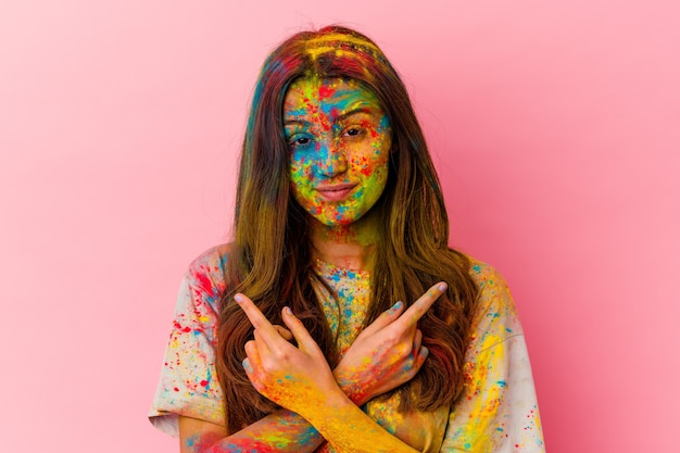 Mujer india joven que celebra el festival sagrado aislado en puntos blancos hacia los lados, está tratando de elegir entre dos opciones.