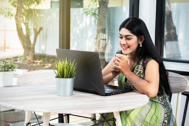 Mujer india con laptop en la mesa con café