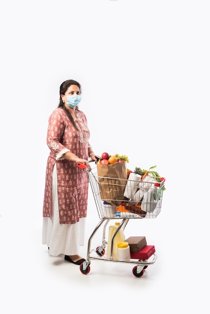 Mujer india de mediana edad con carrito de compras o carretilla llena de verduras y frutas comestibles Foto de cuerpo entero aislado sobre fondo blanco.