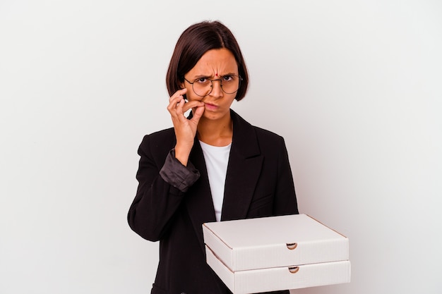 Mujer india de negocios joven sosteniendo pizzas aisladas con los dedos en los labios guardando un secreto.