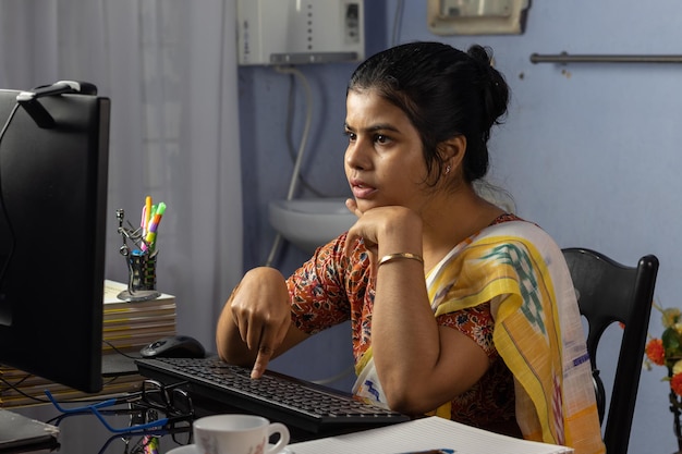 Mujer india en saree trabajando en la computadora en casa trabajo desde casa concepto