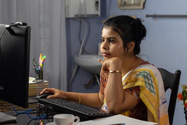 Mujer india en saree trabajando en la computadora en casa trabajo desde casa concepto