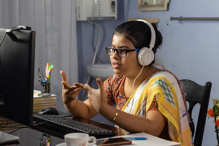 Foto mujer india en saree trabajando en la computadora y hablando por internet desde casa enseñando en línea