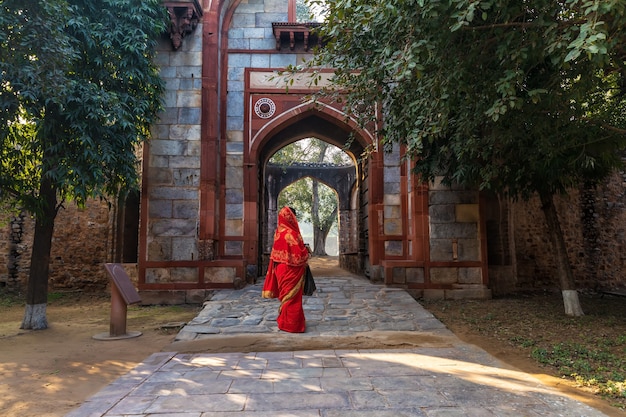 Mujer india en sari rojo cerca de Arab Ki Sarai Gateway de la tumba de Humayun, Nueva Delhi, India.