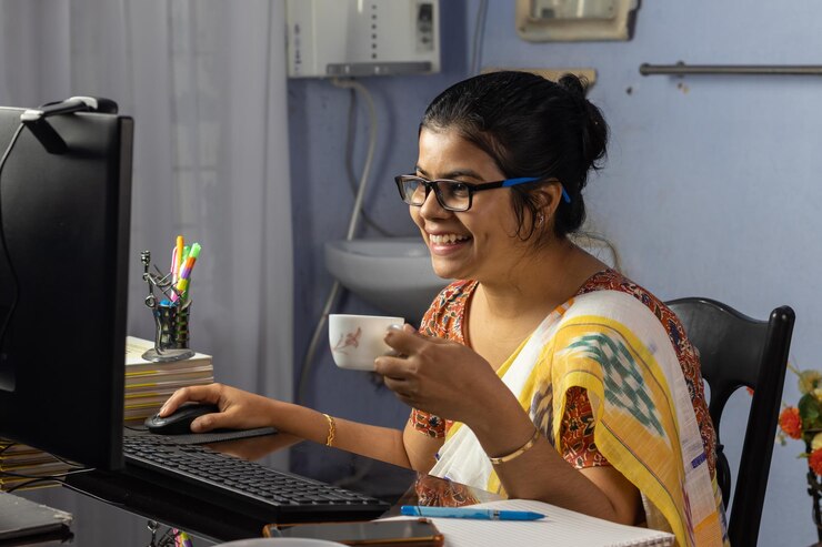 Foto mujer india en sari trabajando en la computadora y tomando té en casa trabajo desde el concepto de casa