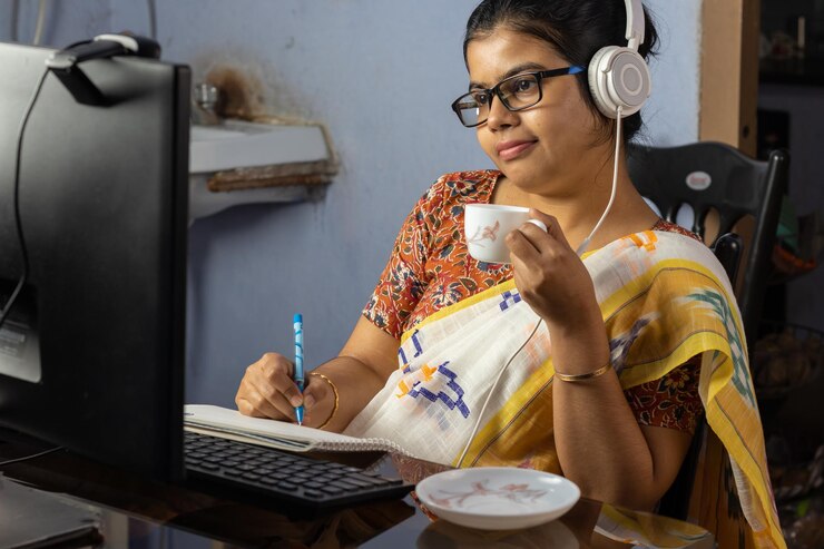Foto mujer india en sari trabajando en la computadora y tomando té en casa trabajo desde el concepto de casa