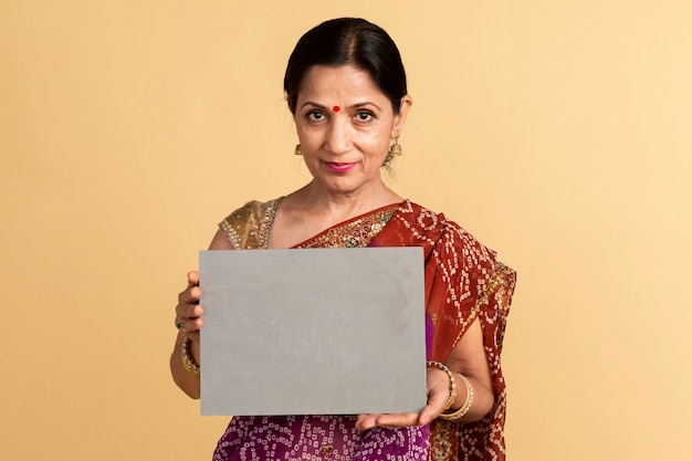 Foto mujer india en un sari tradicional sosteniendo una maqueta de papel