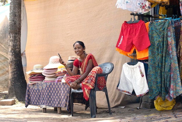 Mujer india vendedora ambulante en una pequeña tienda de ropa en Agonda