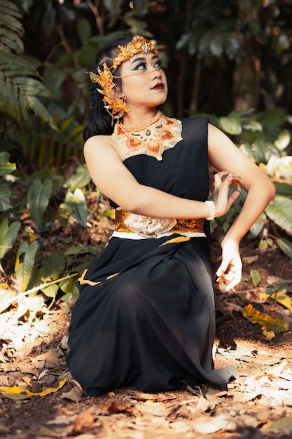 Mujer india con un vestido negro con una corona dorada y un collar dorado en el cuerpo