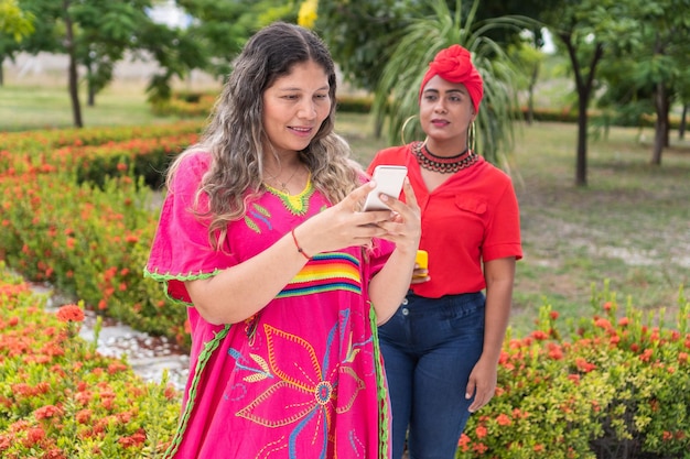 Mujer indígena usando un celular y esperando a su amiga