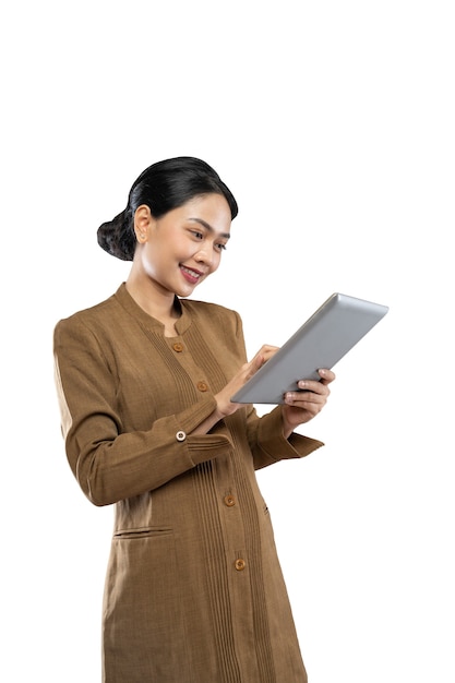 Mujer indonesia en uniforme de funcionario de pie usando una tableta de computadora