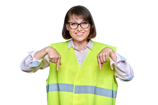 Mujer industrial en chaleco de seguridad sobre fondo blanco aislado apuntando hacia abajo copyspace