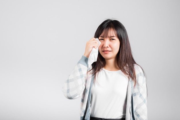 Mujer infeliz de mal humor su llanto limpia la mucosidad con un tejido, el estrés femenino joven y hermoso se siente estornudo sinusal usa una toalla para limpiarse las lágrimas de los ojos, toma de estudio aislada en fondo blanco con espacio para copiar