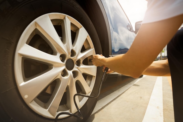 Mujer infla el neumático Mujer comprobando la presión de los neumáticos y bombeando aire en el neumático de la rueda del coche