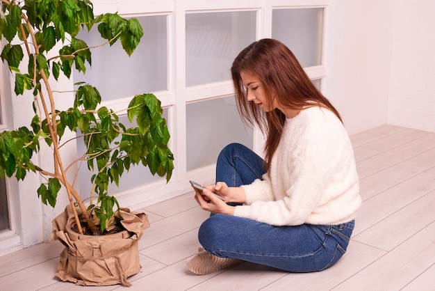 Mujer con información de búsqueda de teléfono sobre el cultivo de plantas en casa