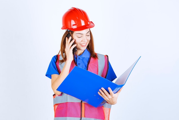 Mujer ingeniero en casco rojo hablando por teléfono.