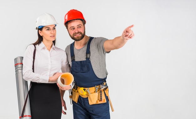 Mujer ingeniero y constructor apuntando hacia afuera