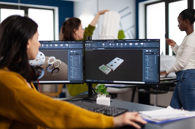 Mujer ingeniero industrial que trabaja en pc con dos pantallas de monitores que muestran software cad