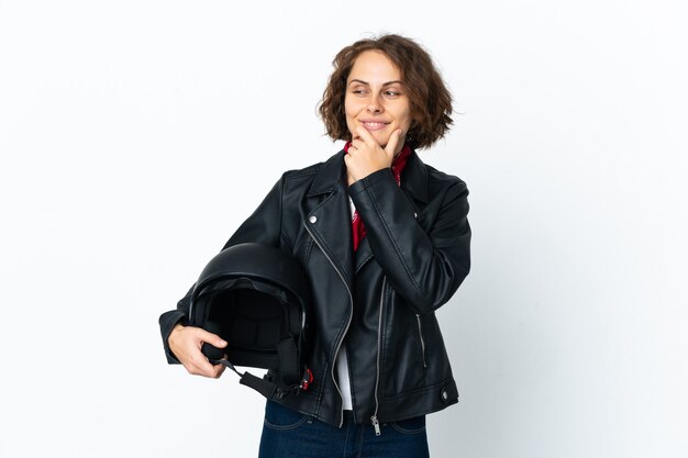 Mujer inglesa sosteniendo un casco de motocicleta aislado mirando hacia el lado y sonriendo