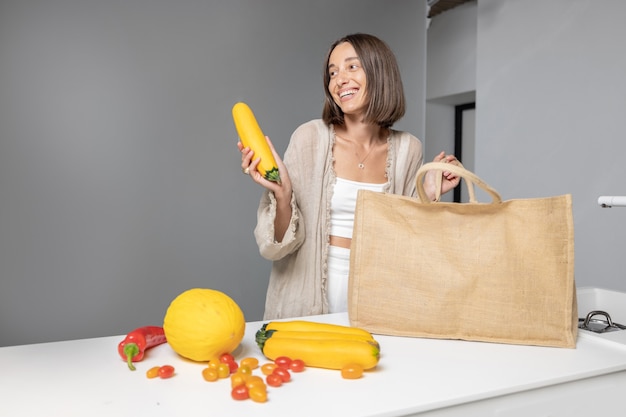 Mujer con ingredientes de alimentos crudos en la cocina moderna en casa