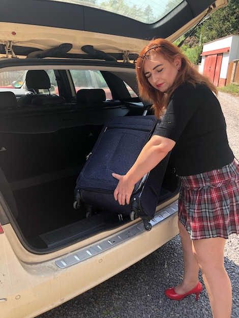 Foto mujer insertando equipaje en el maletero del coche