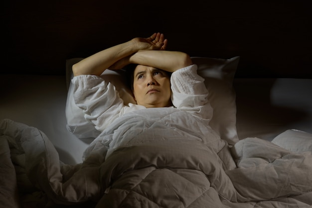 Mujer con insomnio acostada en la cama con los ojos abiertos