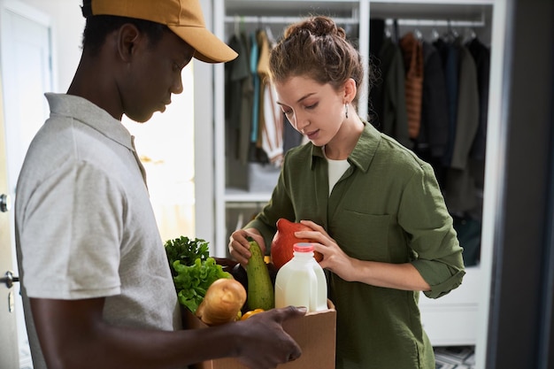 Foto mujer inspeccionando la entrega de comestibles frescos en casa