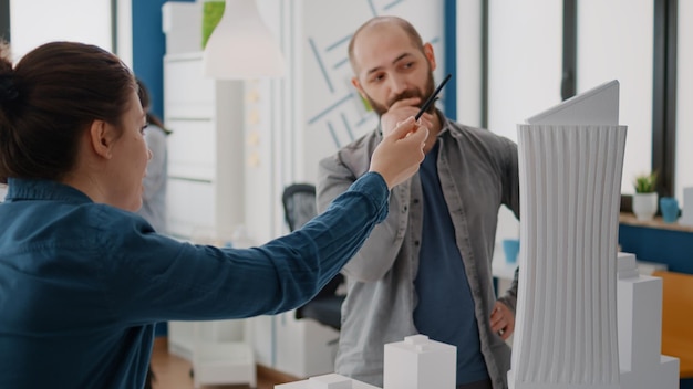 Mujer intercambiando ideas con el hombre para diseñar el plan y los planos del modelo de construcción, trabajando en la estructura y el diseño de la construcción. Equipo de colegios que planifican el desarrollo de proyectos urbanos.