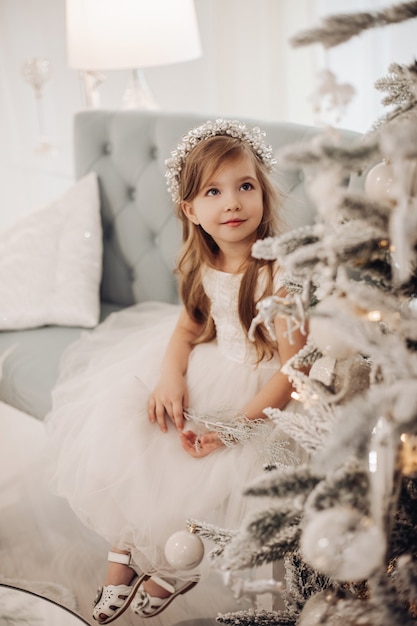 Mujer interesada con un anillo de cabeza de flor y mirando el árbol decorado