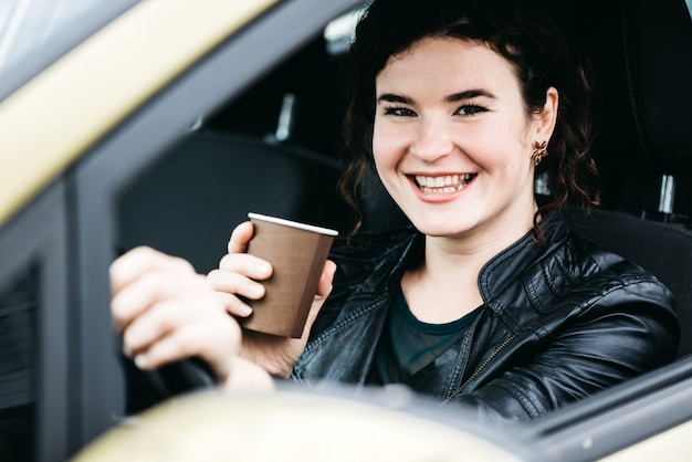 La mujer en el interior del coche mantiene la rueda que da vuelta alrededor de sonrisa