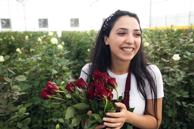 Mujer en invernadero con ramo de rosas.