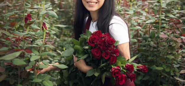 Mujer en invernadero con ramo de rosas.