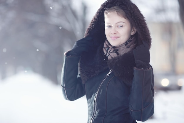 Mujer de invierno en un abrigo de piel en la nieve afuera