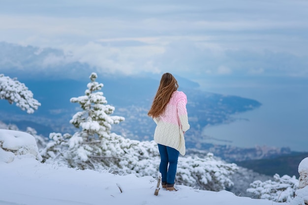 Una mujer en invierno sola en la cima de una montaña nevada