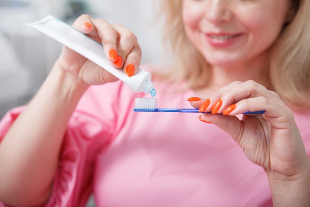 Mujer irreconocible apretando pasta de dientes en su cepillo de dientes