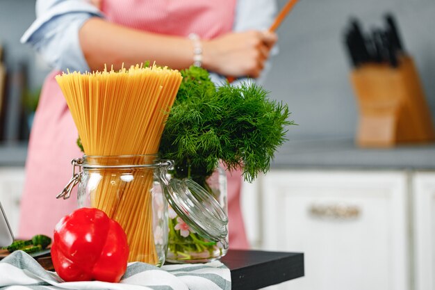 Mujer irreconocible cocinando algo cerca de la estufa en la cocina de cerca