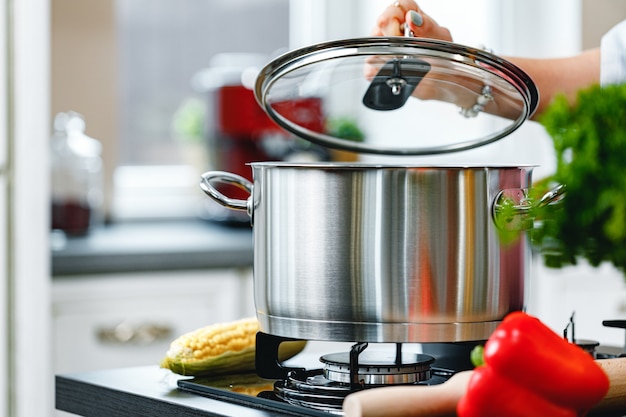 Mujer irreconocible cocinando algo cerca de la estufa en la cocina de cerca