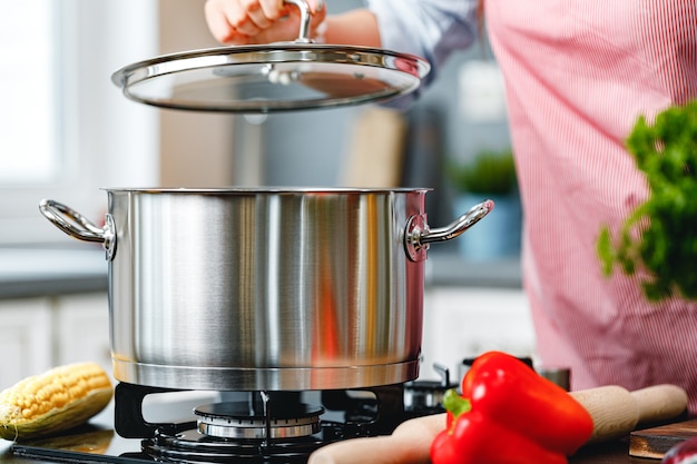 Mujer irreconocible cocinando algo cerca de la estufa en la cocina de cerca