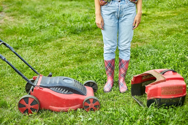 Mujer irreconocible con una cortadora de césped en el jardín de su casa, mujer de jardinero trabajando, hermoso paisaje de verano, luz del sol, gran diseño para cualquier propósito, concepto de jardinería