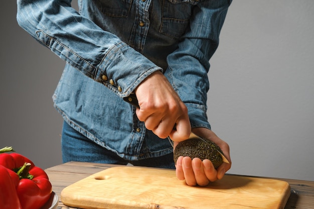 Mujer irreconocible cortando aguacate con un cuchillo en la cocina