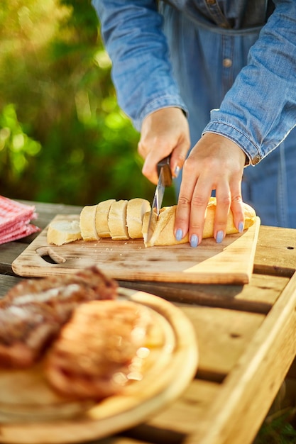 Mujer irreconocible cortando pan para bruschetta en tablero de madera