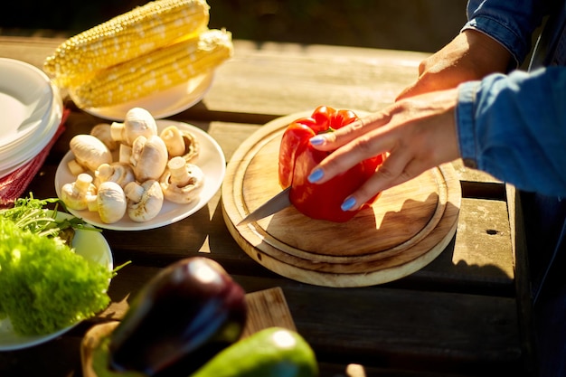 Mujer irreconocible cortando verduras frescas de pimienta en tablero de madera