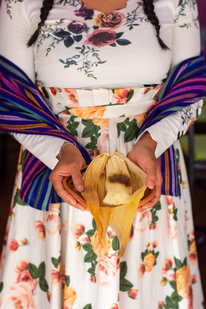 Mujer irreconocible con un delicioso tamal mexicano