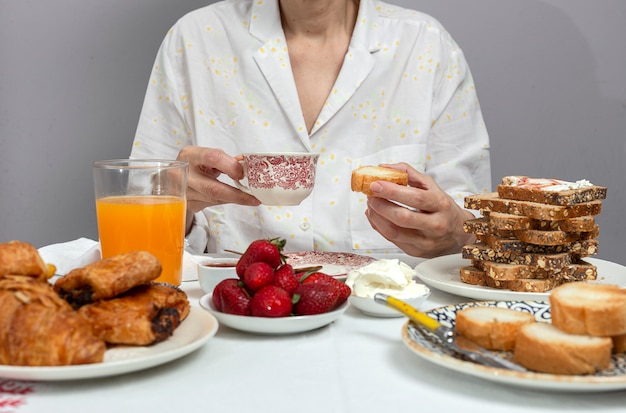 Mujer irreconocible desayunando en pijama en casa