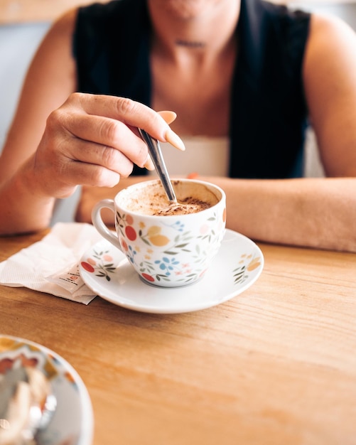 Foto una mujer irreconocible con uñas largas revuelve un café con una cuchara pequeña