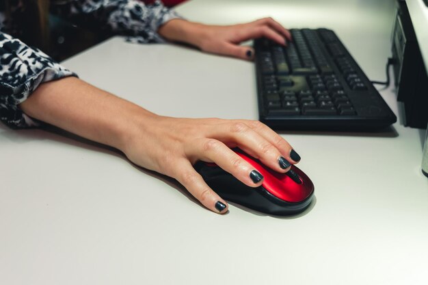 Mujer irreconocible en una oficina usando un mouse y teclado de computadora