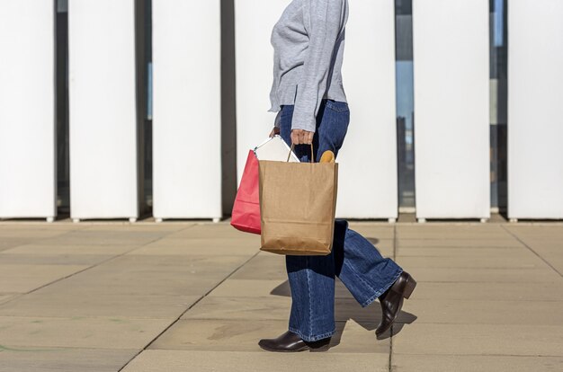 Mujer irreconocible con papel reciclable llevar bolsa de comida