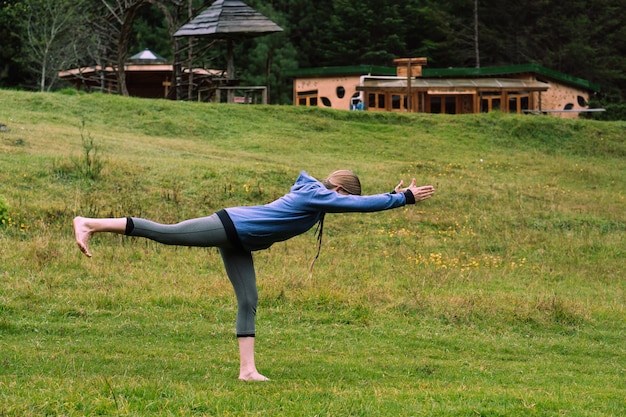 Mujer irreconocible con ropa deportiva y practicando yoga en un bosque.