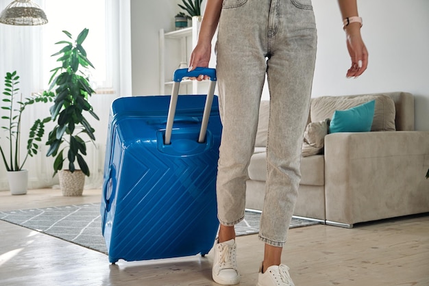 Mujer irreconocible saliendo de casa con una maleta yendo de viaje o de vacaciones