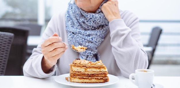 Mujer irreconocible sentada en una mesa de café con una rebanada de pastel de café ignorando la dieta